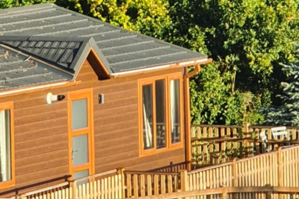 a tiny house with a wooden fence and trees at The Lodge at Meadow Hope in Hereford
