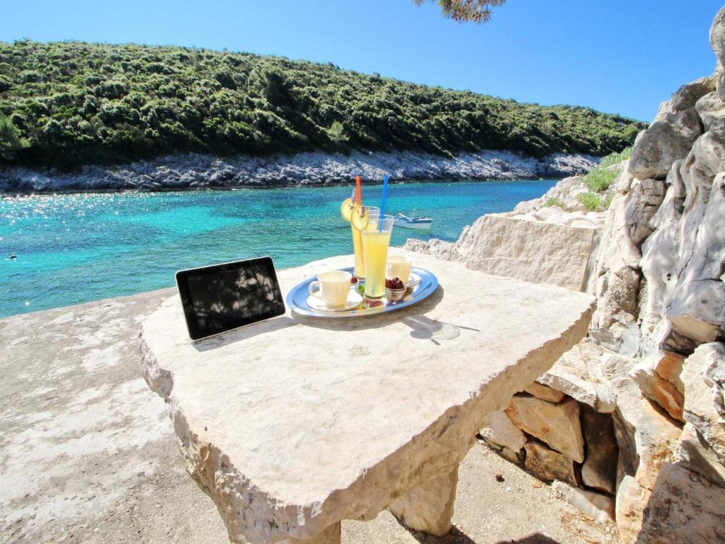 a table with a drink and a laptop on it next to the ocean at Oasis of Paradise in Žrnovo