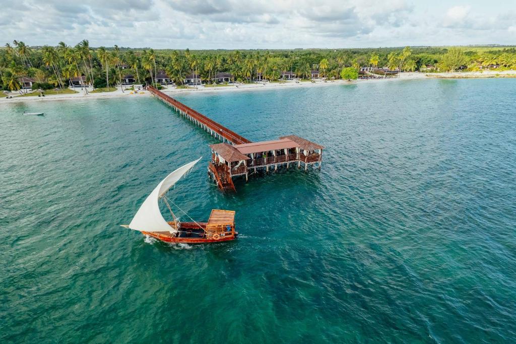 a boat in the water next to a beach at The Residence Zanzibar in Kizimkazi