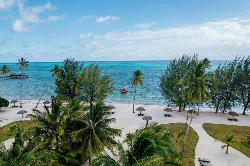an empty beach with umbrellas and the ocean at The Residence Zanzibar in Kizimkazi