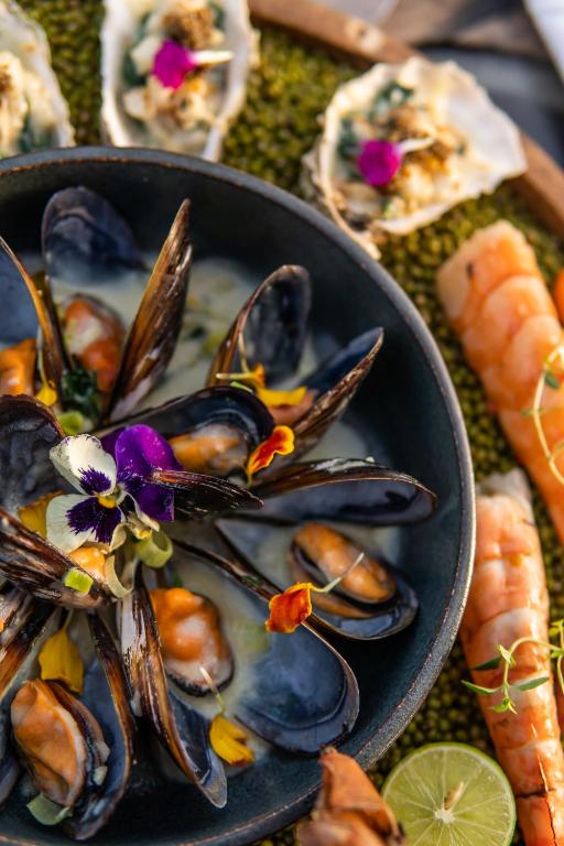 a black bowl of mussels and carrots on a table at The Residence Zanzibar in Kizimkazi