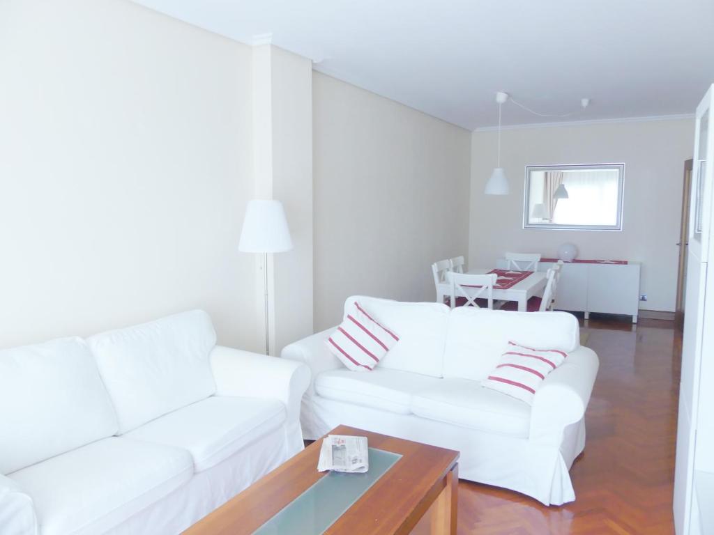 a white living room with two white couches and a table at Apartamento luminoso, funcional y amplio en zona hospitalaria in Pamplona