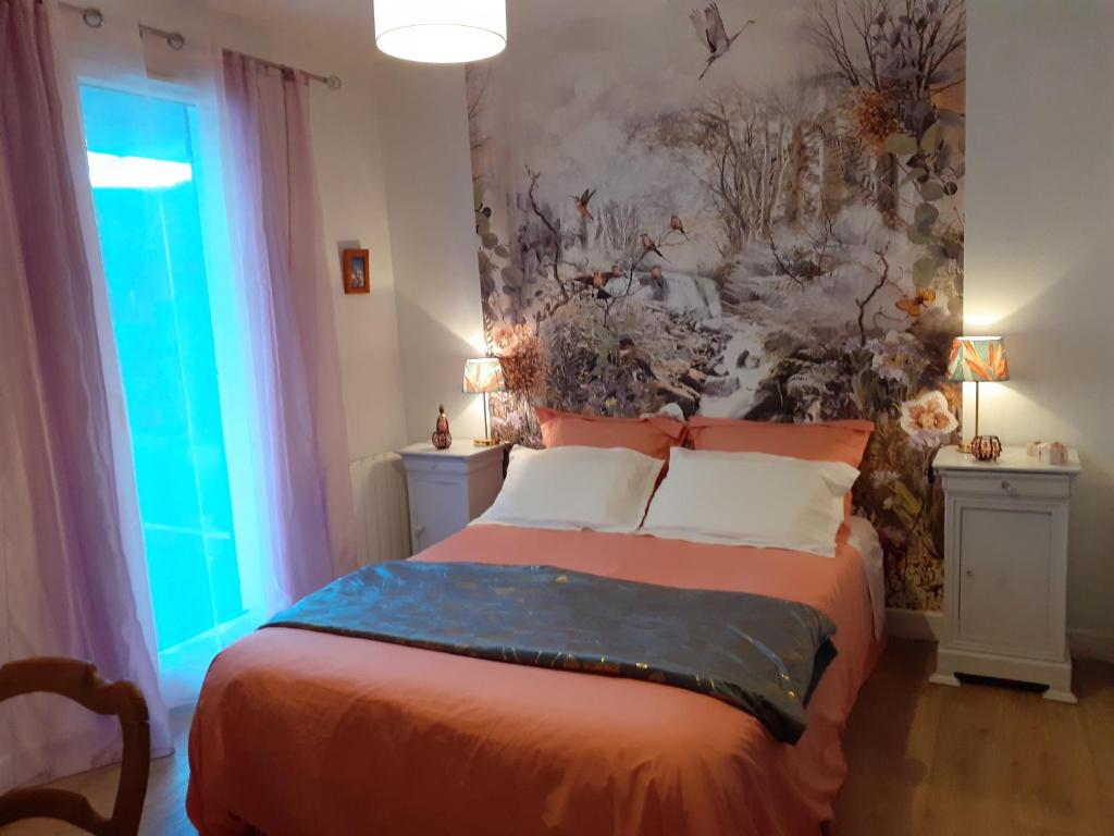 a bedroom with a bed with a painting on the wall at Les Oiseaux chambre d'hôtes in Saint-Florent-sur-Cher