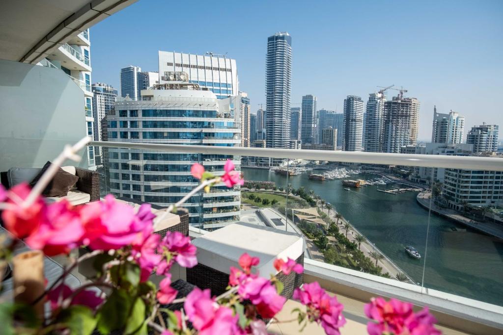 d'un balcon avec des fleurs roses offrant une vue sur la ville. dans l'établissement WSuites - Big Terrace with Beautiful Marina View, à Dubaï