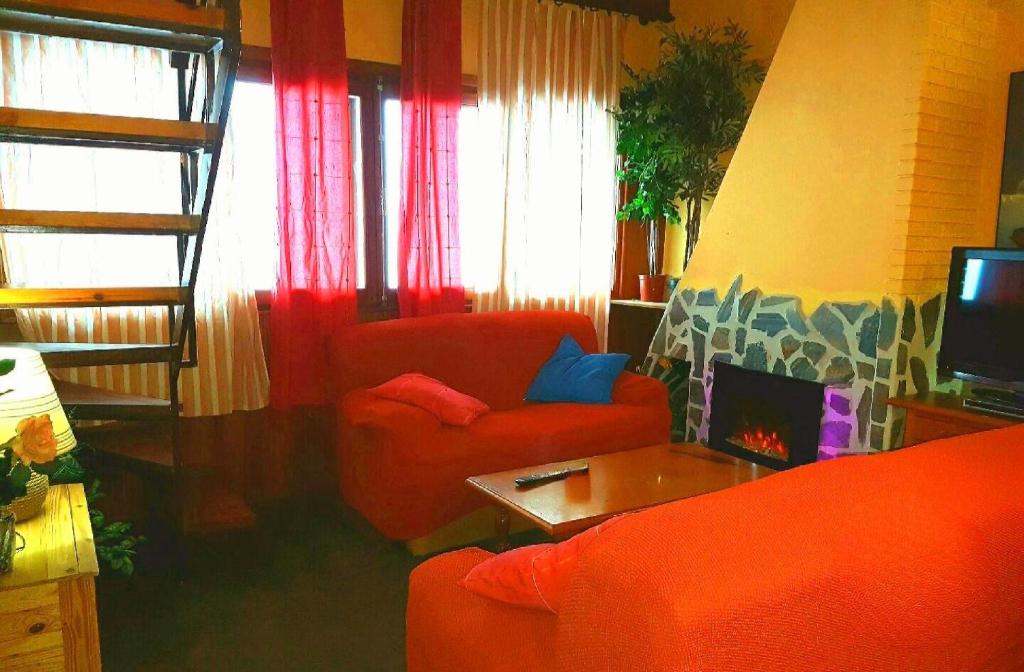 a living room with two red chairs and a television at Apartment de las Nieves in Sierra Nevada