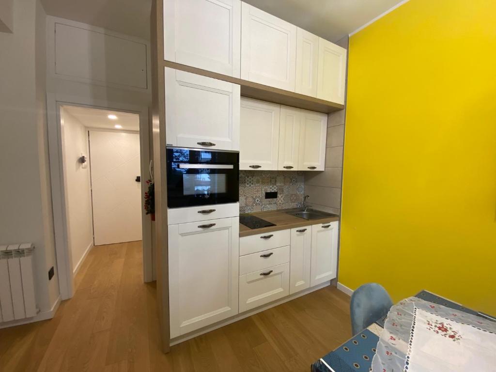 uma cozinha com armários brancos e uma parede amarela em Sendy Home Roccaraso 3 em Roccaraso