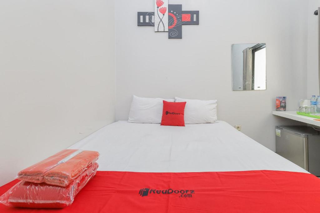 RedDoorz Plus At K23 Rungkut Madya في سورابايا: سرير أبيض كبير ومخدة حمراء عليه