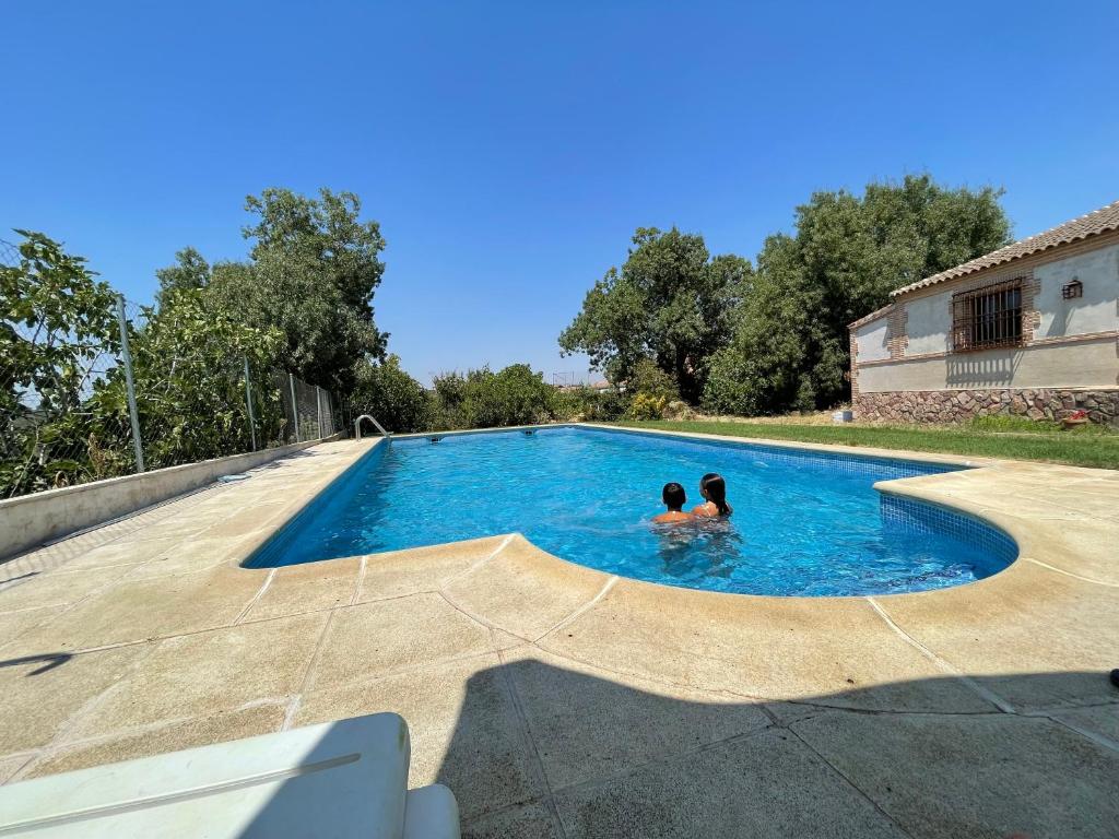 two people are swimming in a swimming pool at Casa Rural El Cantueso in Hontanar