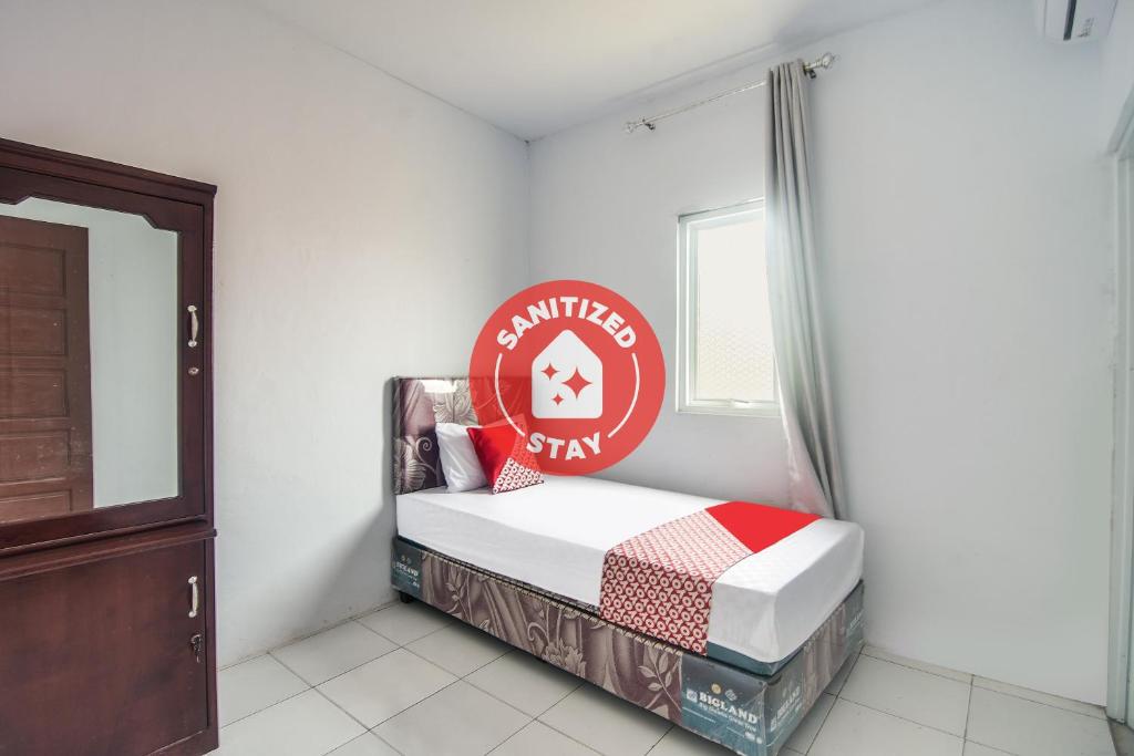 a bedroom with a bed with a sign on the wall at SPOT ON 92000 3m Kost Dan Homestay in Manado