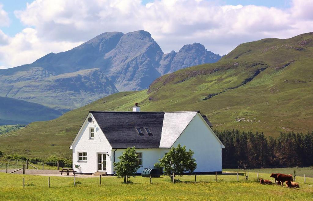 a white house in a field with mountains in the background at Strath Glebe in Kilbride