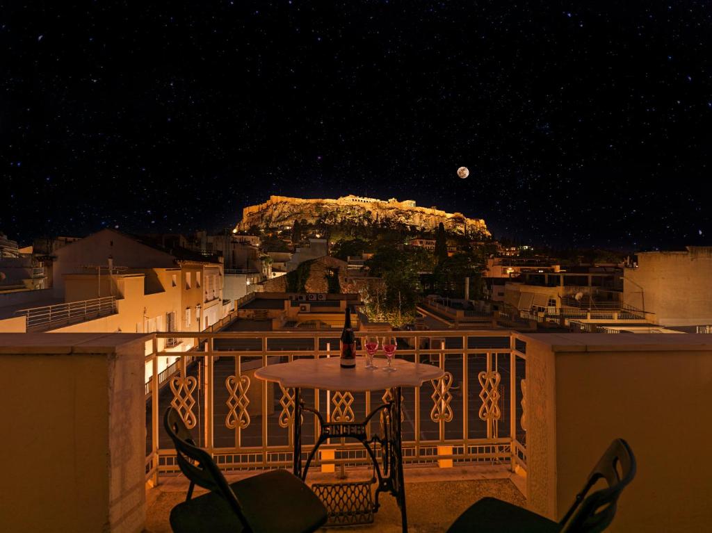 a table and chairs on a balcony at night at Luxurious Top Floor Acropolis View Loft in Plaka - Newly Refurbished in Athens