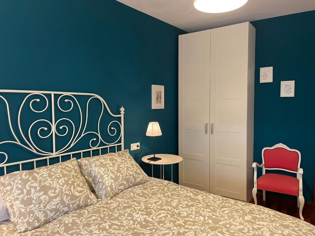 1 dormitorio azul con 1 cama y 1 silla roja en Apartamento corredoira, en Monforte de Lemos