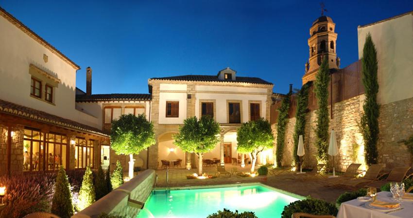 a mansion with a swimming pool in front of a building at Hotel Puerta de la Luna in Baeza