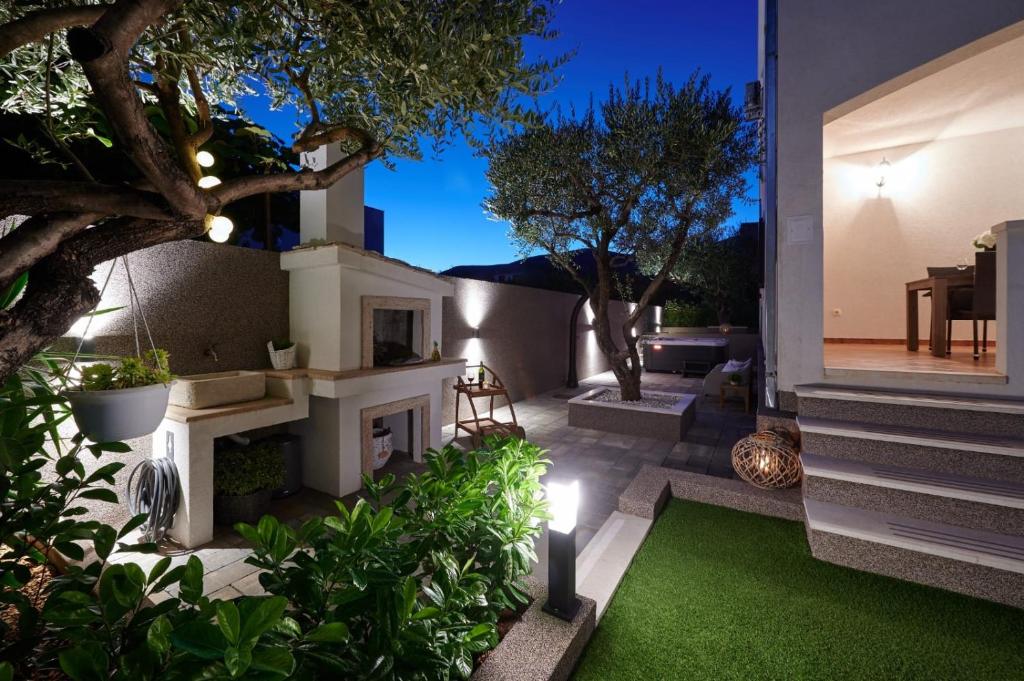 einen Hinterhof mit einem Garten mit Kamin und Gras in der Unterkunft Villa Demonta in Trogir