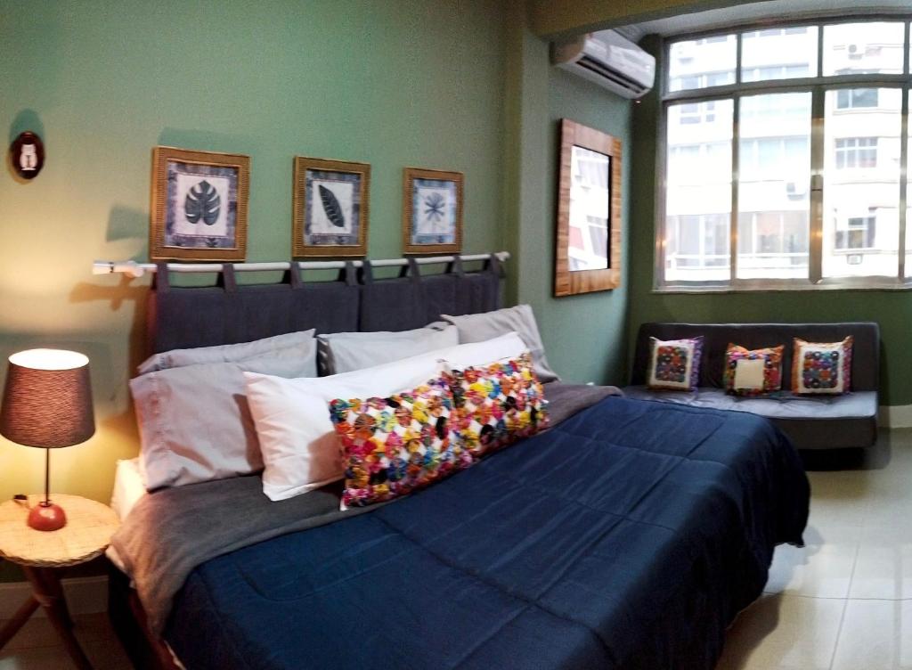 Un dormitorio con una gran cama azul con almohadas coloridas en Loft, en Río de Janeiro