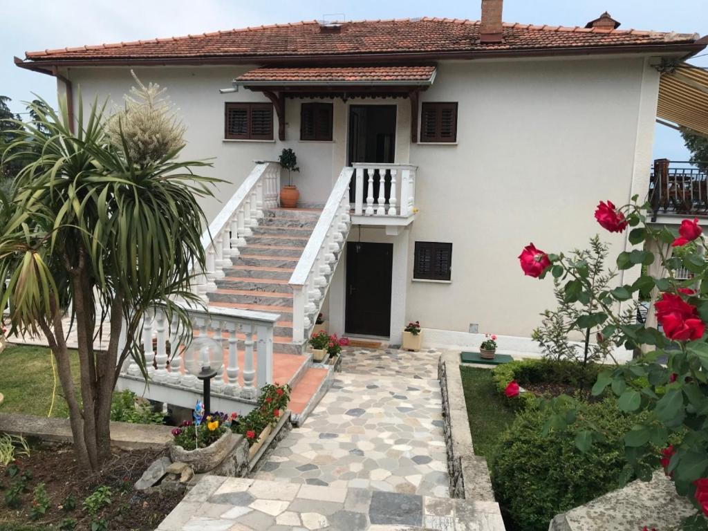 una casa blanca con escaleras y flores en un patio en Apartment in Lovran with terrace, air conditioning, WiFi, washing machine 3735-2 en Lovran