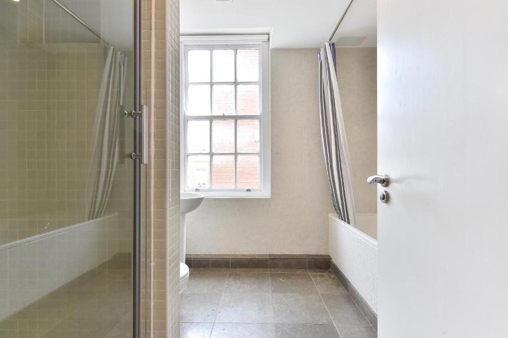 ein Bad mit einer Dusche und einem Fenster in der Unterkunft Camden Town apartments in London