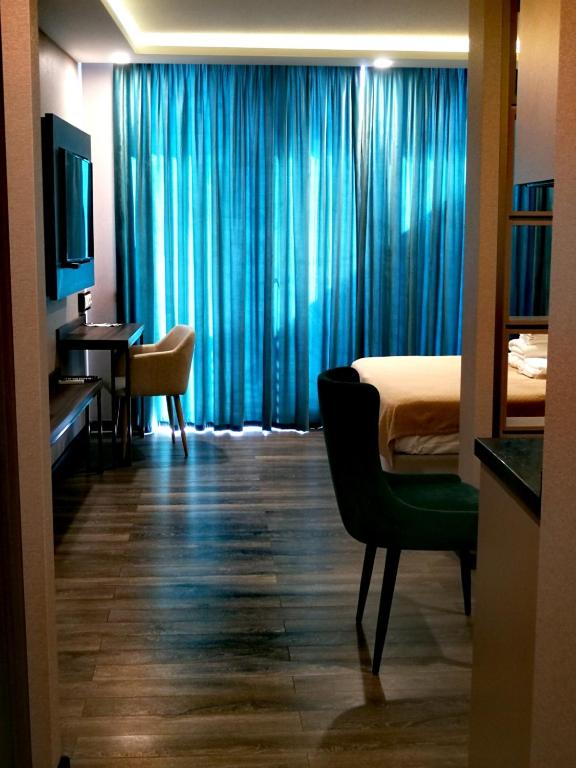 a bedroom with blue curtains and a bed and a desk at Luxury Hotel Suite Apartment in Batumi