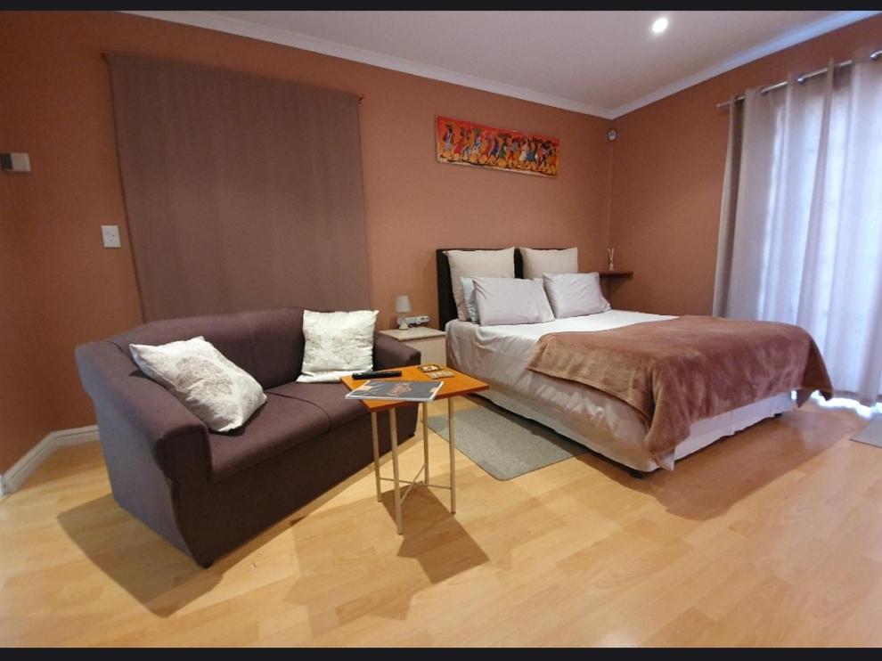 1 dormitorio con 1 cama y 1 sofá en Birds Holiday Accommodation 1, en Ciudad del Cabo