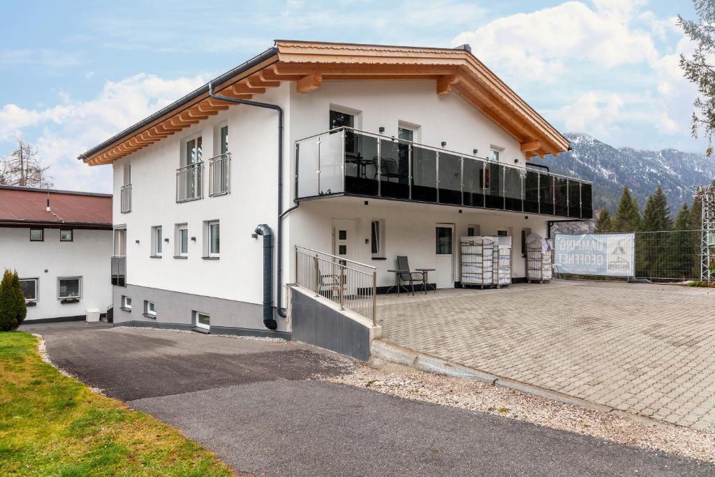 Cette grande maison blanche possède un balcon dans une allée. dans l'établissement Ferienwohnung Zugspitze, à Ehrwald