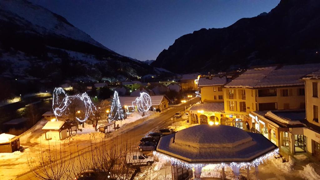 Una ciudad iluminada por la noche con luces de Navidad en Hôtel Restaurant Glaizette, en LʼArgentière-la-Bessée