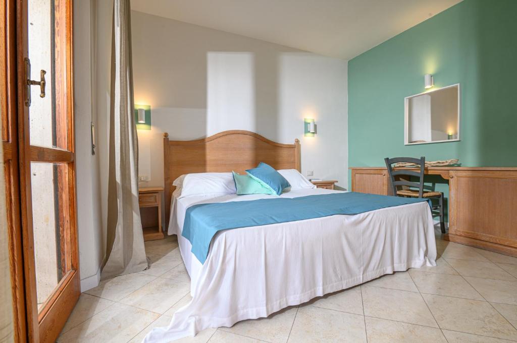 sypialnia z łóżkiem z niebieską pościelą i stołem w obiekcie Elbamar Marina Di Campo w mieście Marina di Campo