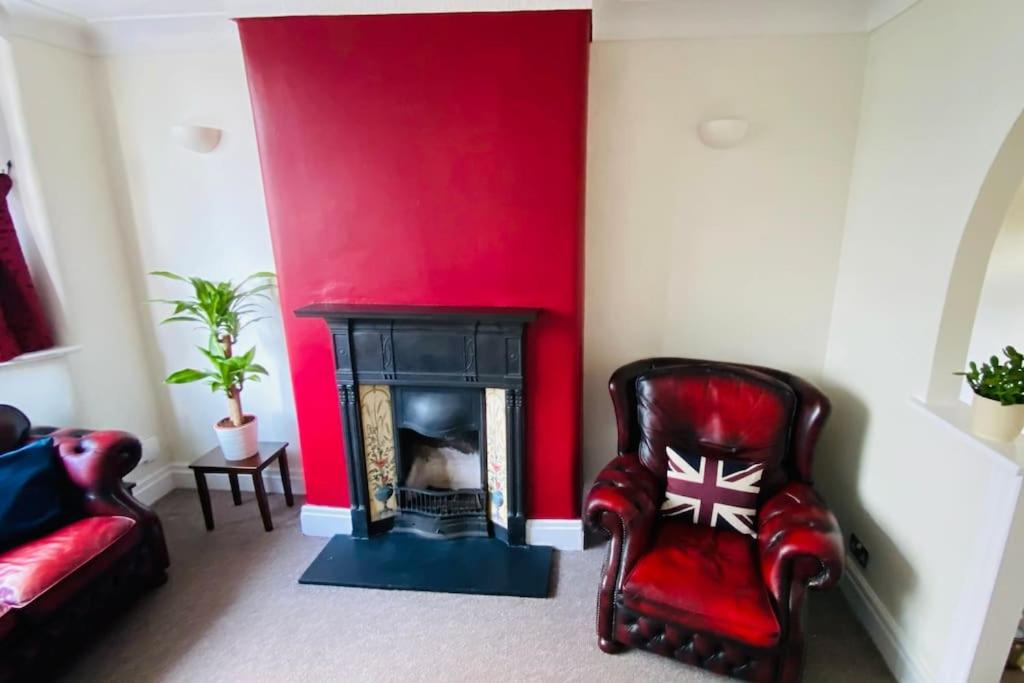 a living room with red walls and a fire place at 3 BR Property in Prestwich 15 mins from Manchester City Centre Garden Free parking Superfast WIFI Netflix in Manchester