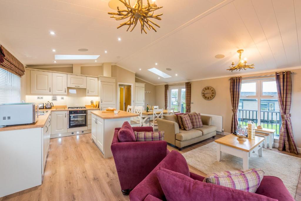 een grote keuken en een woonkamer met paars meubilair bij St Tinney Farm Cornish Cottages & Lodges, a tranquil base only 10 minutes from the beach in Otterham