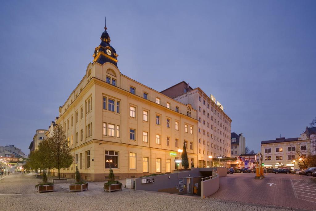 un grande edificio giallo con una torre dell'orologio in cima di Imperial Hotel Ostrava a Ostrava