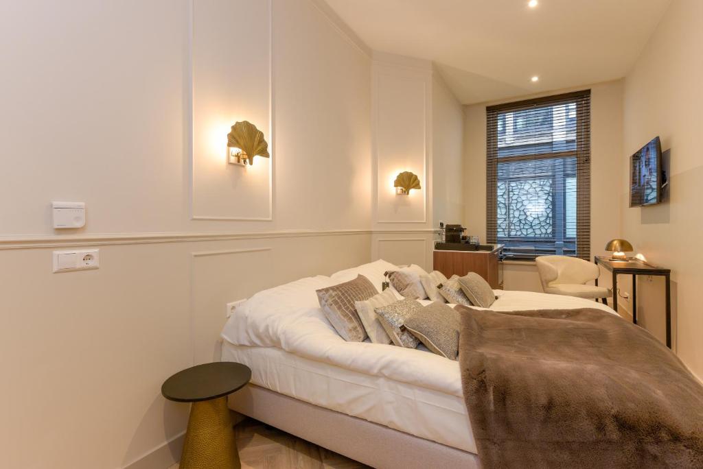 a white bedroom with a bed and a chair at Novallure City Centre in The Hague