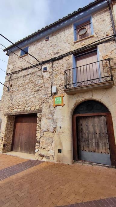 un edificio de piedra con 2 puertas de garaje y balcón en Casa rural completa LA CRIVA 11pers, en Crivillén