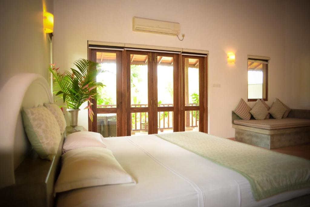 a bedroom with a large white bed and a window at Kingfisher Bamboo Garden Villa in Unawatuna