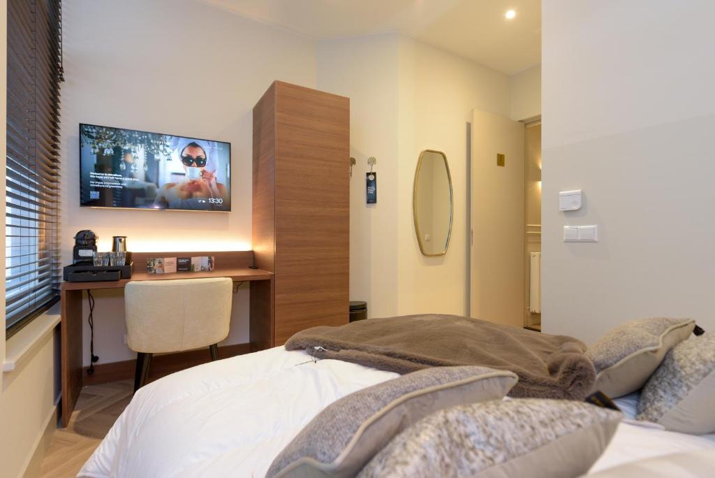 a bedroom with a bed and a desk with a tv at Novallure City Centre in The Hague