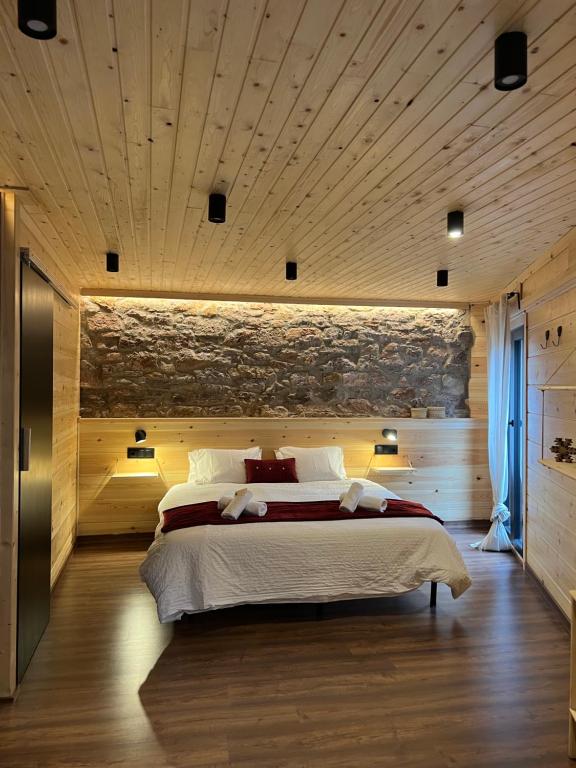 um quarto com uma cama grande e uma parede de pedra em Fonda Peremiquel em Castellar de NʼHug