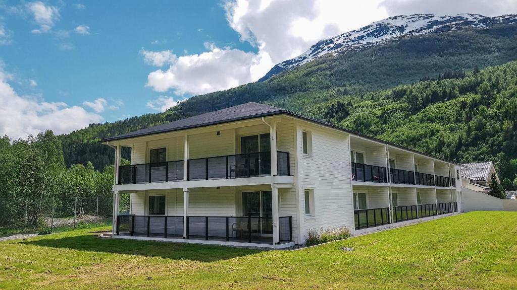 un gran edificio blanco con balcones y una montaña en Loen Apartments, en Loen
