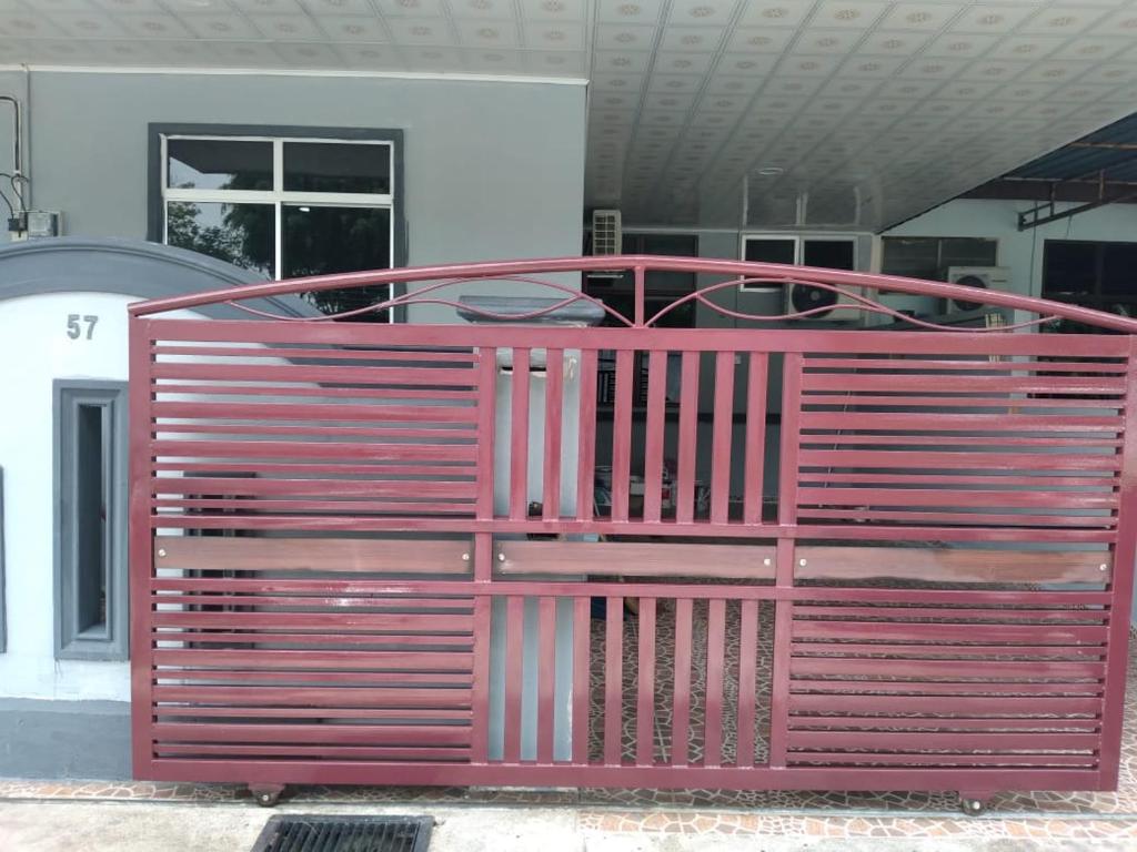 a red metal gate in front of a building at D'illahs Homestay in Alor Setar