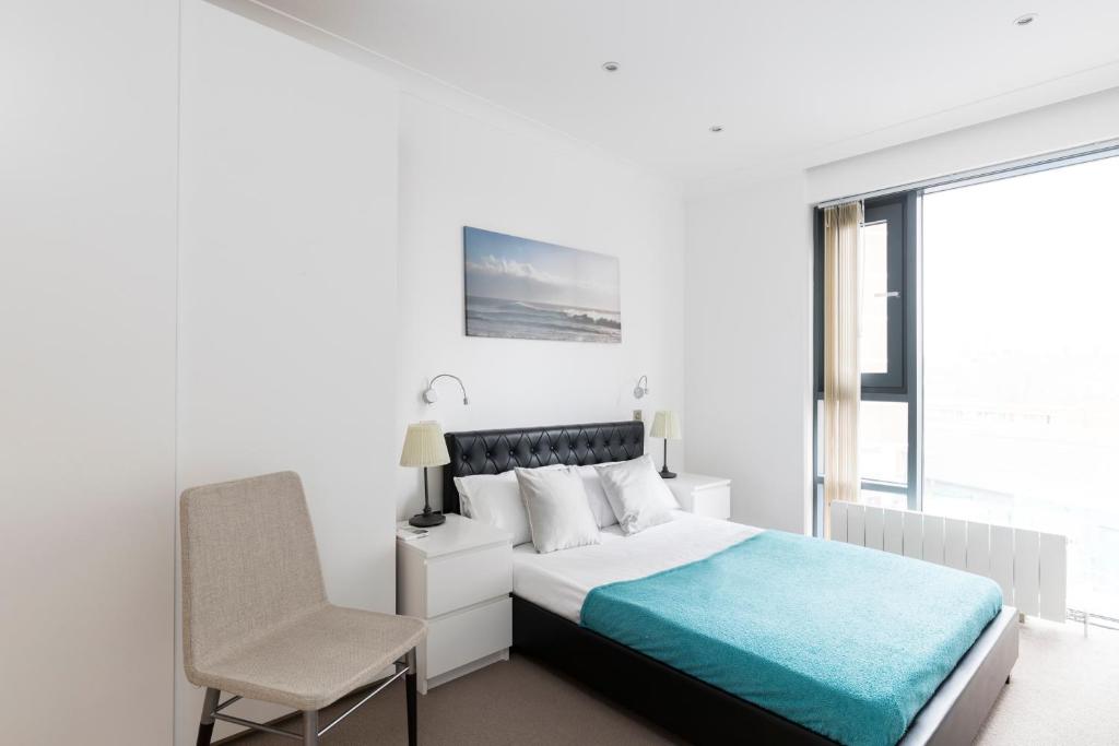 a white bedroom with a bed and a chair at City Apartments in London