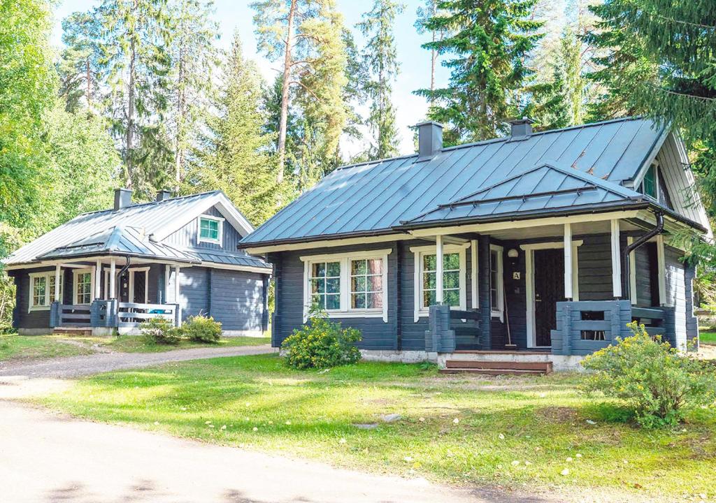 una pequeña casa azul con un porche junto a una casa en Tervakosken Tervaniemi hirsimökki & oma sauna en Tervakoski
