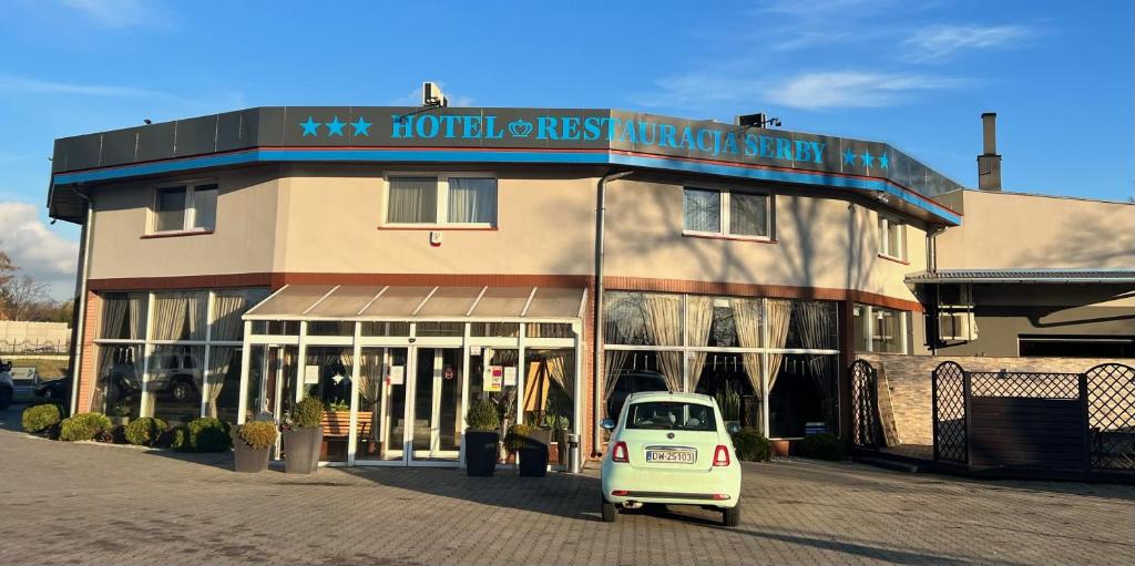 a small white car parked in front of a building at Hotel Serby in Głogów