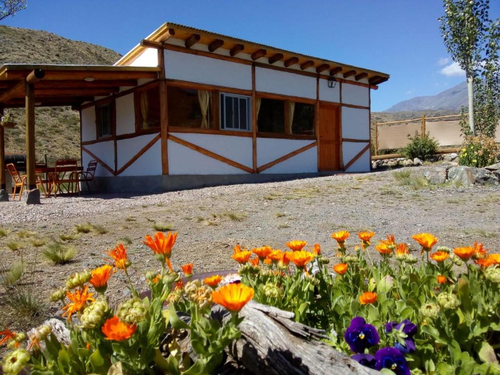 a house with flowers in front of it at Camino & Piedra - Cabaña de Montaña in Potrerillos