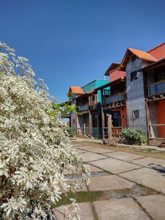 a tree with white flowers in front of some buildings at Pousada Cachoeiras do Cipó in Serra do Cipo