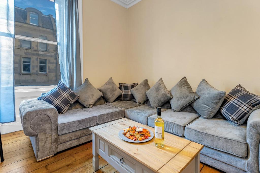 愛丁堡的住宿－Edinburgh City Centre Jasmine Apartment -SLEEPS 7，客厅配有沙发和一张桌子及一瓶葡萄酒