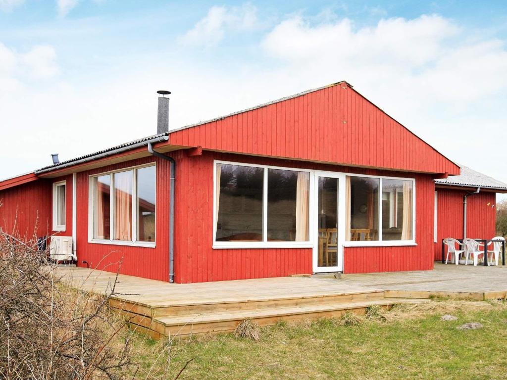 uma casa vermelha com um deque de madeira em frente em Holiday home Hjørring VIII em Hjørring