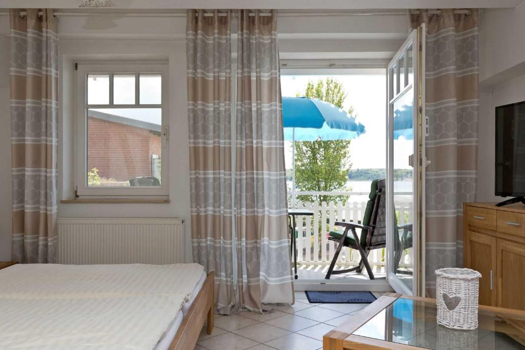 - une chambre avec un lit et un balcon avec un parasol dans l'établissement Kietzspeicher App 05, à Waren