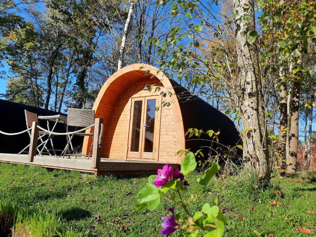 ein kleines Iglu-Haus auf einem Feld mit Bäumen in der Unterkunft 28 Premium Camping Pod in Silberstedt