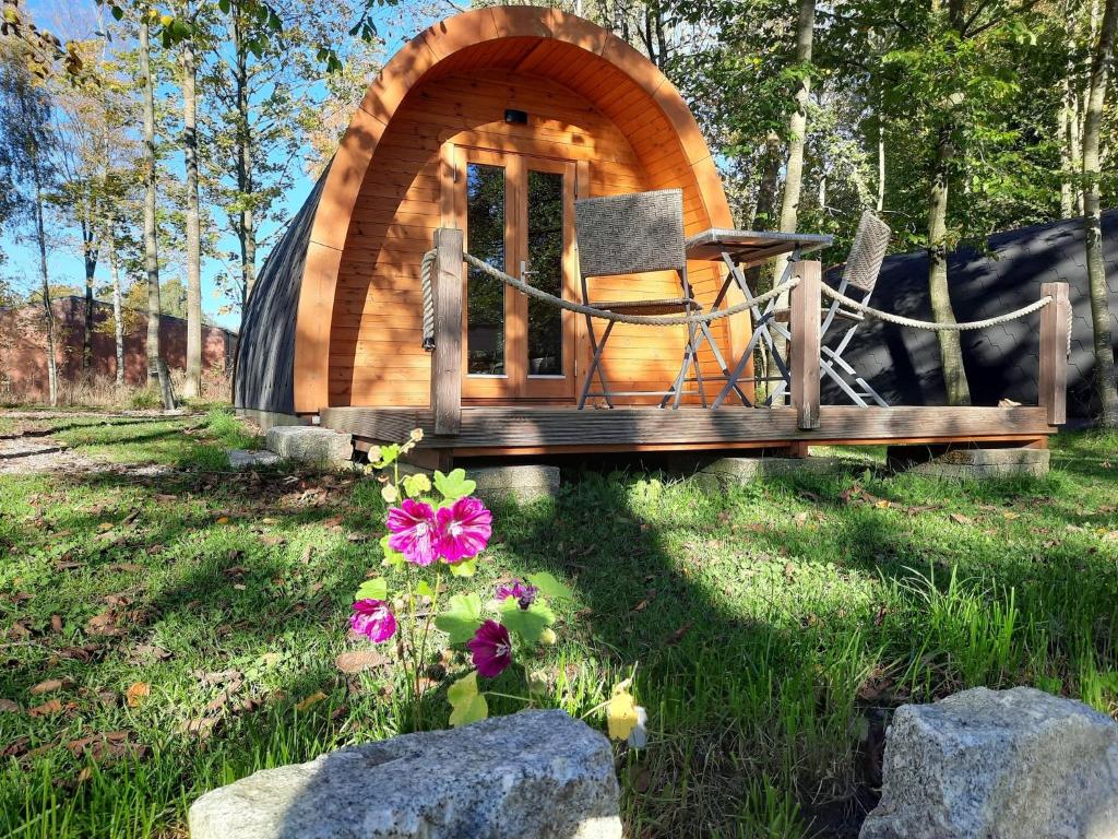 a wooden cabin with a chair in the grass at 29 Premium Camping Pod in Silberstedt