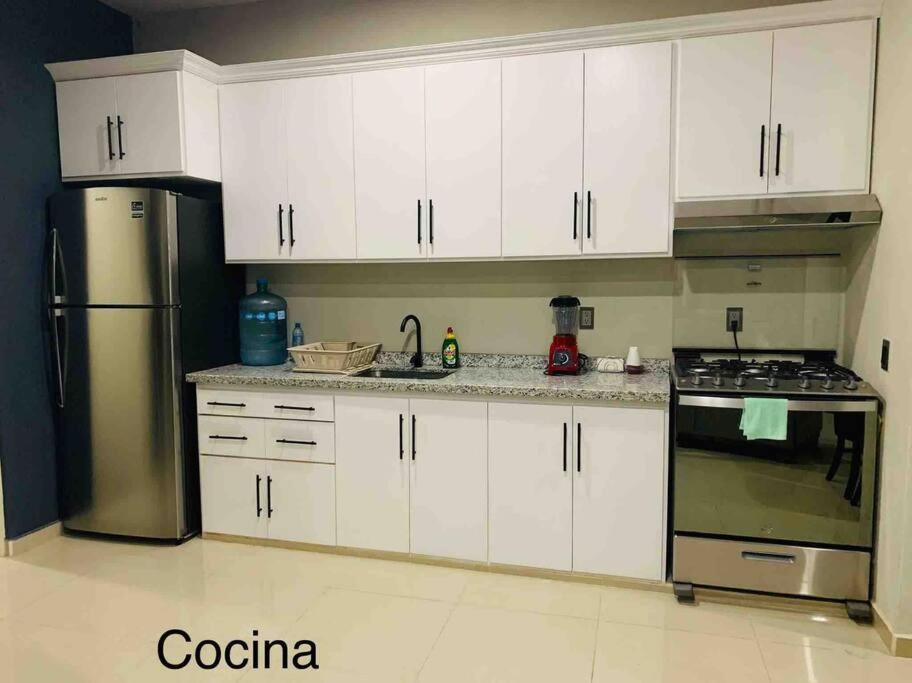 La cuisine est équipée de placards blancs et d'un réfrigérateur en acier inoxydable. dans l'établissement Depa el señor, à Ciudad Guzmán