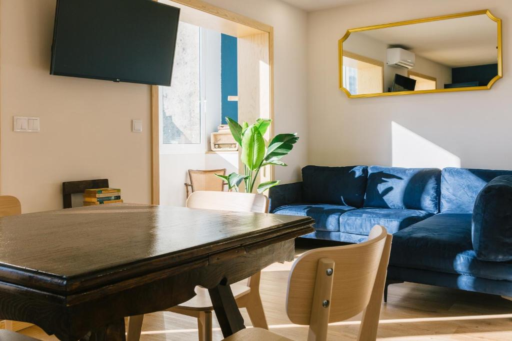 a living room with a table and a blue couch at Campanha Apartment By Porto Stories in Porto