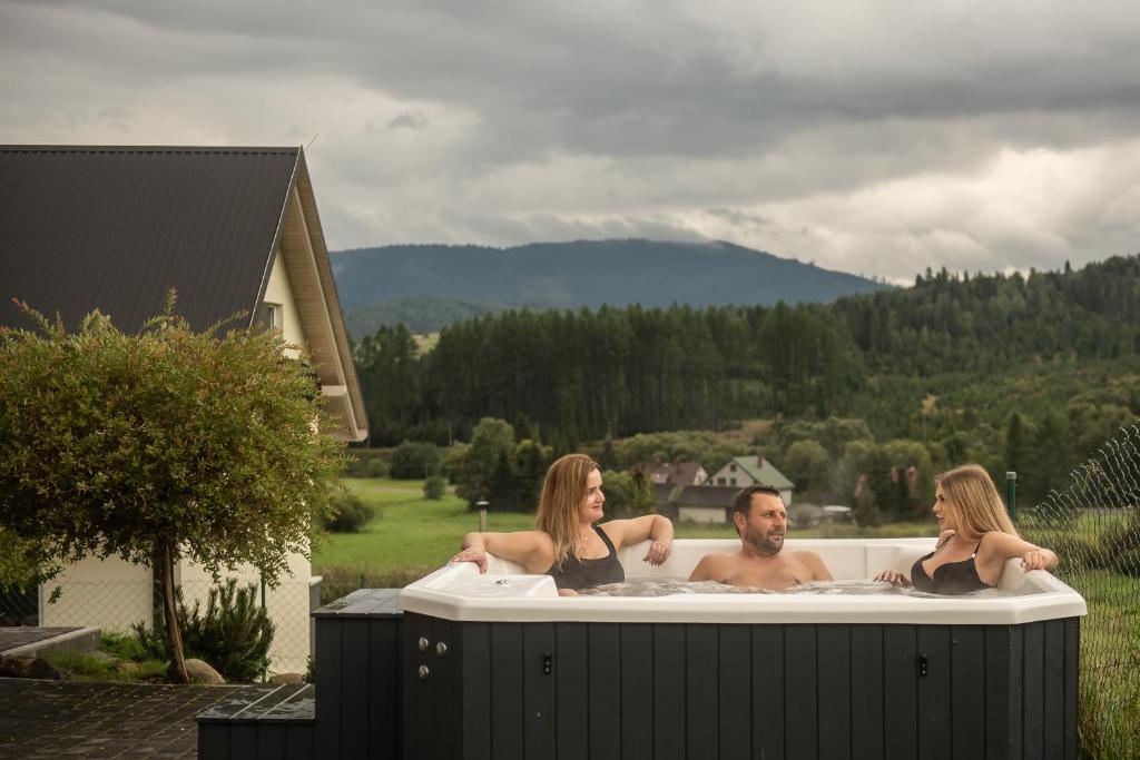 Un uomo e due donne seduti in una vasca da bagno di Villove Domy Spa a Rajcza