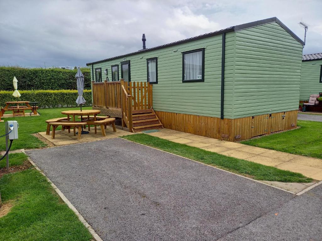 una casa verde con tavolo da picnic e panca di Nala Lodge a Knaresborough